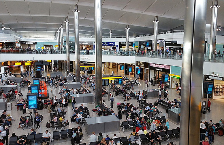 Picture taken inside one of the terminals at London Heathrow Airport / London Airportsshowing lots of people waiting between the shopping area.